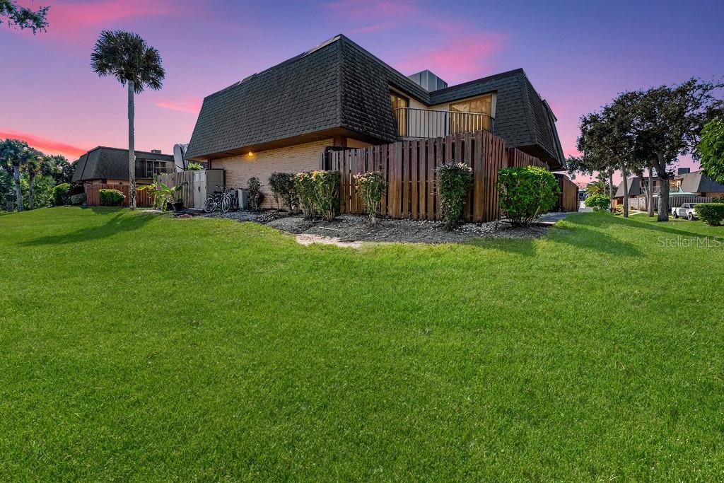 A two-story townhouse with a dark shingled roof and a wooden privacy fence at sunset — 113 CEDAR DUNES DRIVE, NEW SMYRNA BEACH, FL
