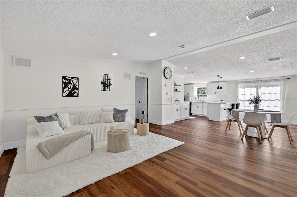 An open-concept living and dining area features white walls, wood flooring, and a white sofa — 3181 COUNTY ROAD 521B, WILDWOOD, FL