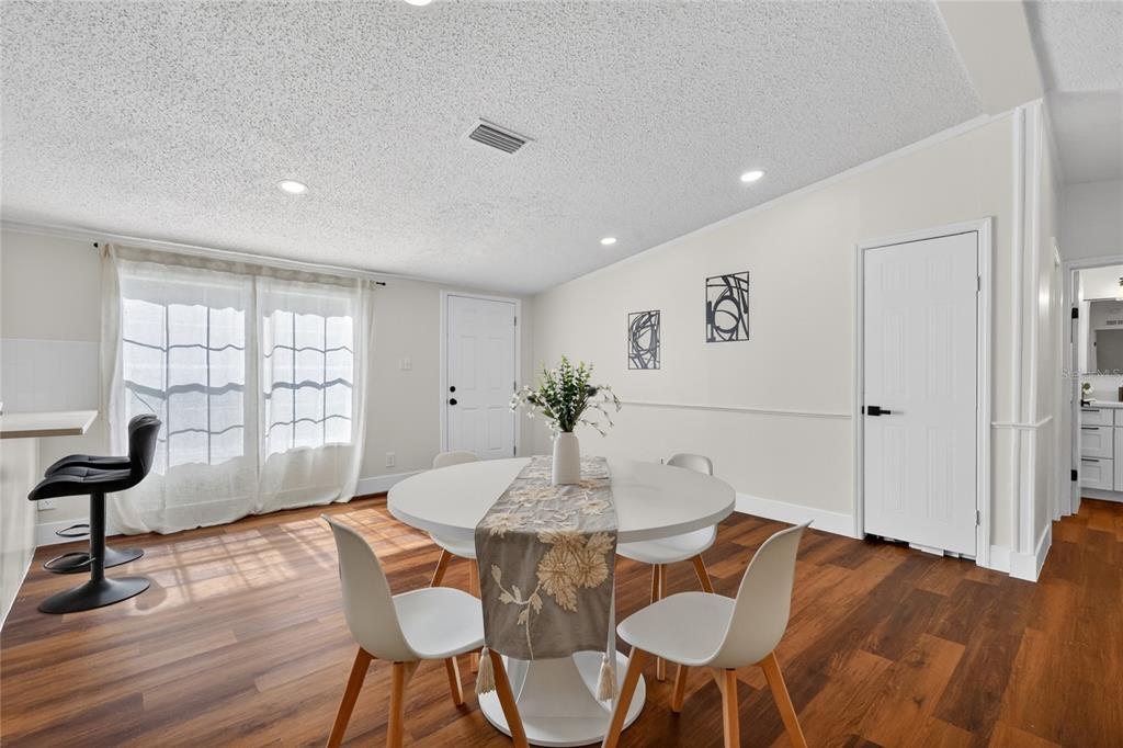 A kitchen features white cabinets, stainless steel appliances, and wood-look flooring — 3181 COUNTY ROAD 521B, WILDWOOD, FL