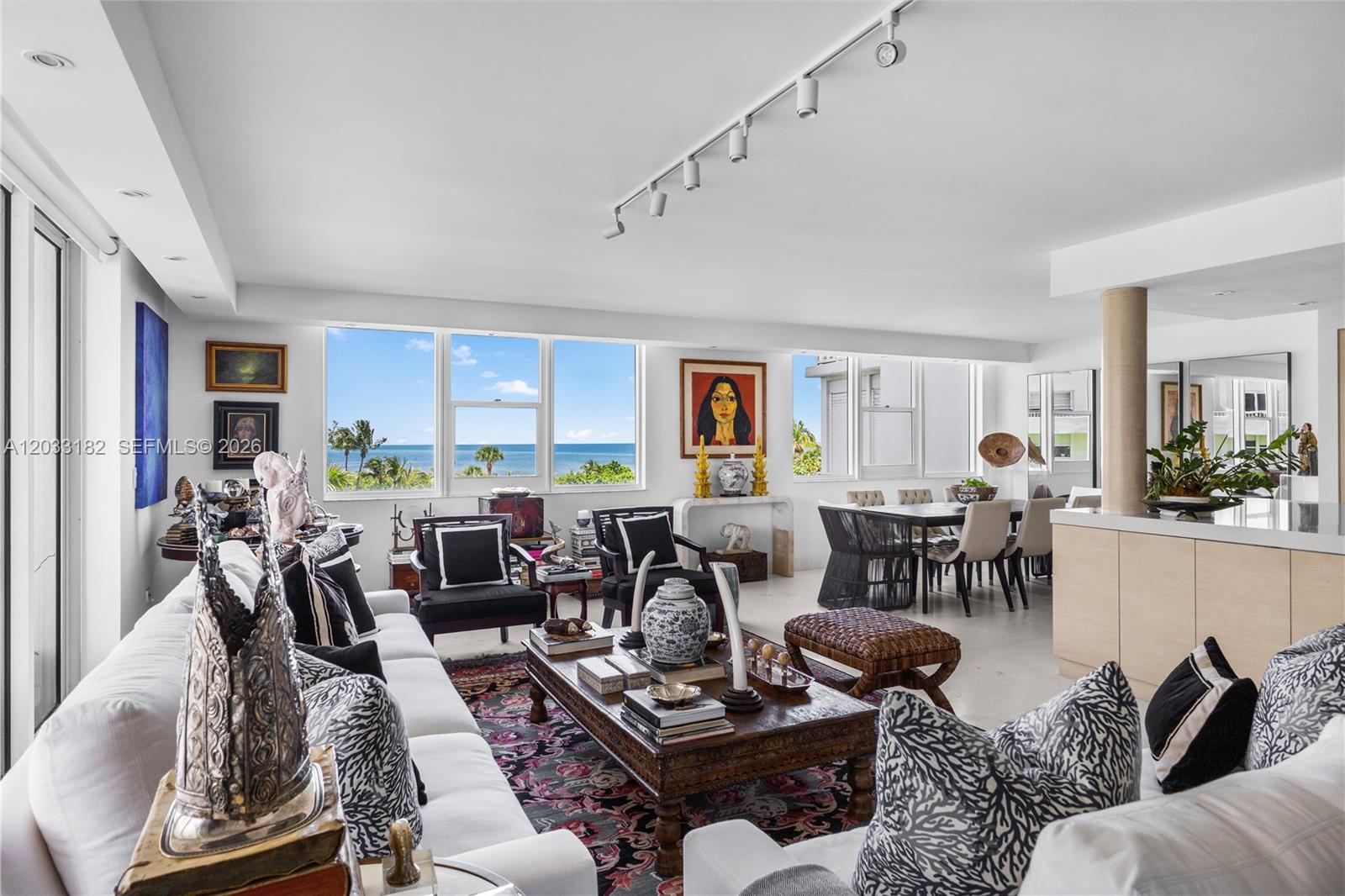 A bright living and dining area features white sofas, a wooden coffee table, and ocean views — 200 Ocean Lane Drive # 409, Key Biscayne FL 33149, KEY BISCAYNE, FL