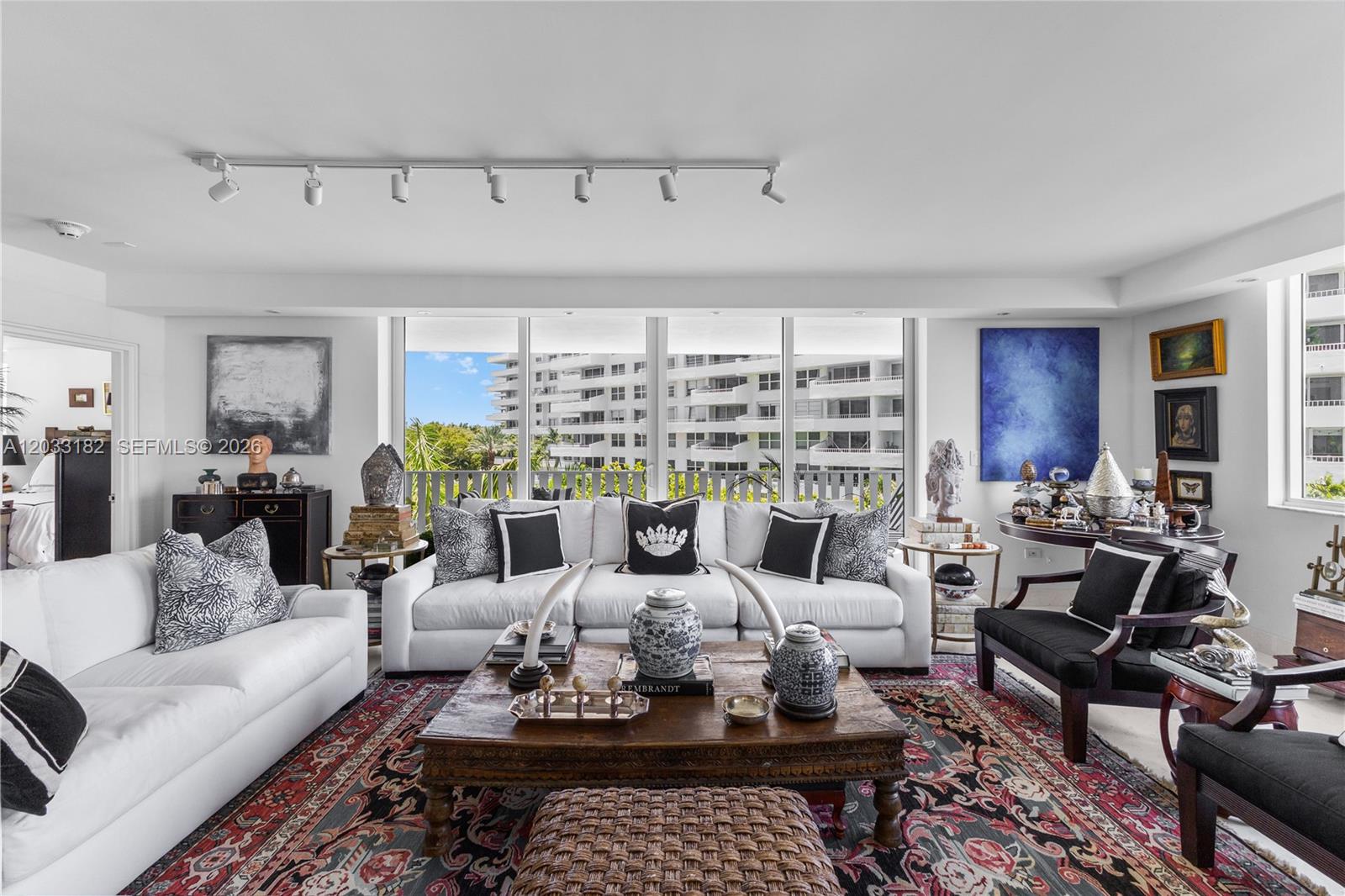 A living room features white sofas, a wooden coffee table, and a large patterned rug — 200 Ocean Lane Drive # 409, Key Biscayne FL 33149, KEY BISCAYNE, FL