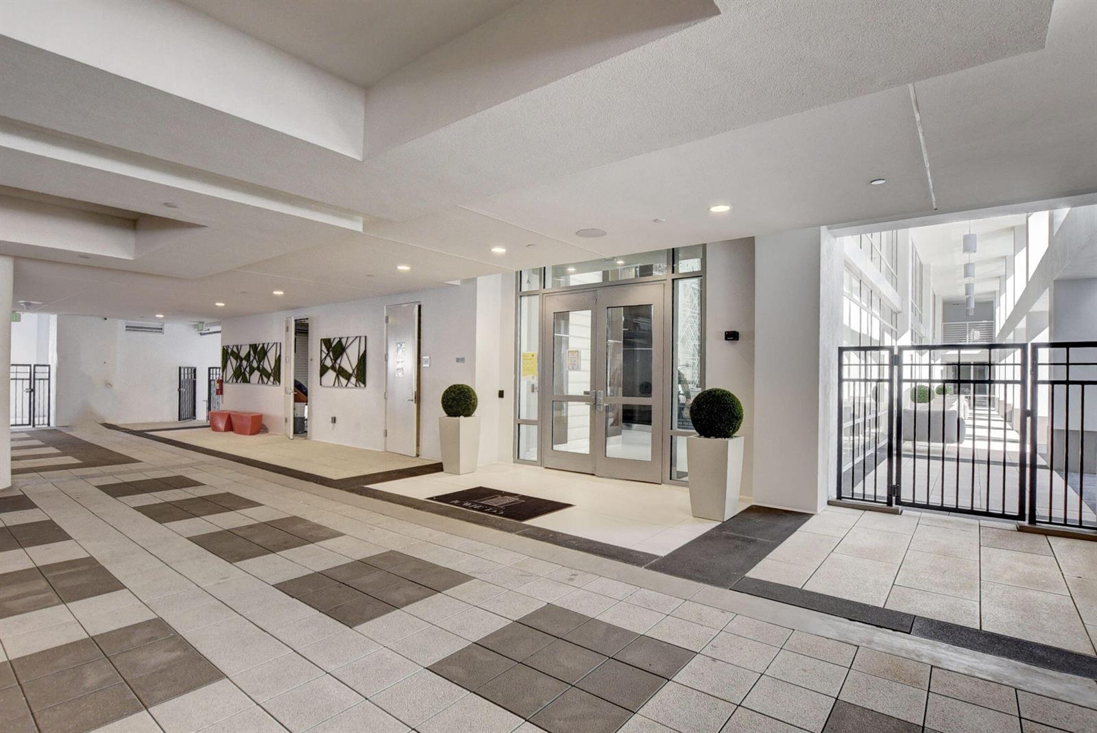 A modern building entrance features glass double doors, potted topiary plants, and tiled flooring — 155 E Boca Raton Road, Boca Raton FL 33432, BOCA RATON, FL