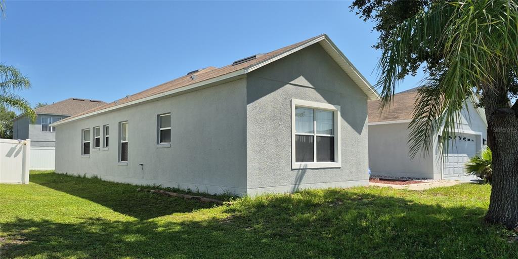 The exterior of a gray stucco house features a gabled roof and a side garage — 560 VICEROY COURT, KISSIMMEE, FL