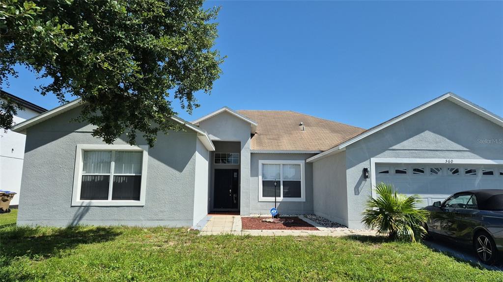 A single-story house with a light gray exterior, a two-car garage, and a front lawn — 560 VICEROY COURT, KISSIMMEE, FL