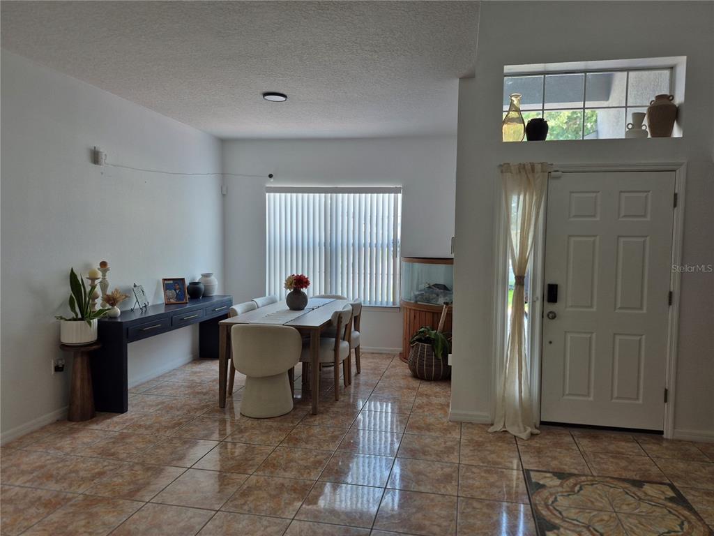 A dining area features tile flooring, a long console table, and a window with blinds — 560 VICEROY COURT, KISSIMMEE, FL