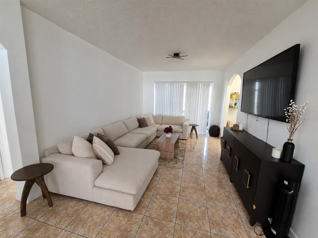 A living room features a large sectional sofa, a dark media console, and tiled floors — 560 VICEROY COURT, KISSIMMEE, FL