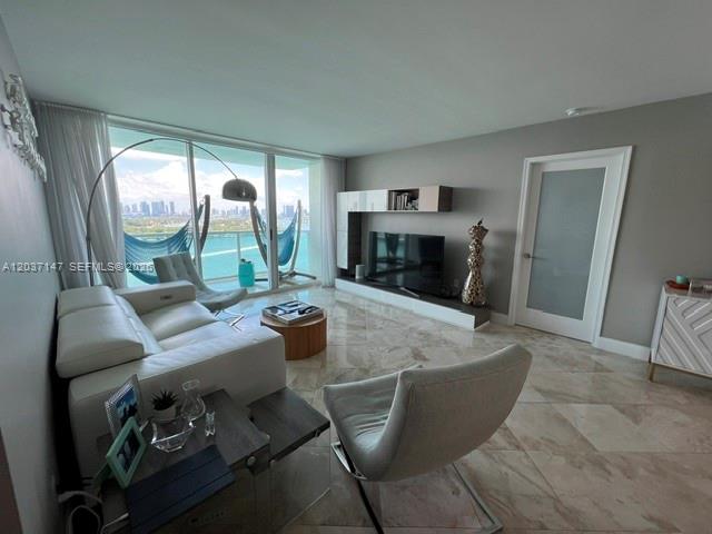 A living room features a white sofa, modern armchair, media console, and floor-to-ceiling windows — 650 West Ave # 2109, Miami Beach FL 33139, MIAMI BEACH, FL