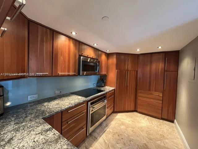 A kitchen features wood cabinets, granite countertops, stainless steel appliances, and light tile flooring — 650 West Ave # 2109, Miami Beach FL 33139, MIAMI BEACH, FL