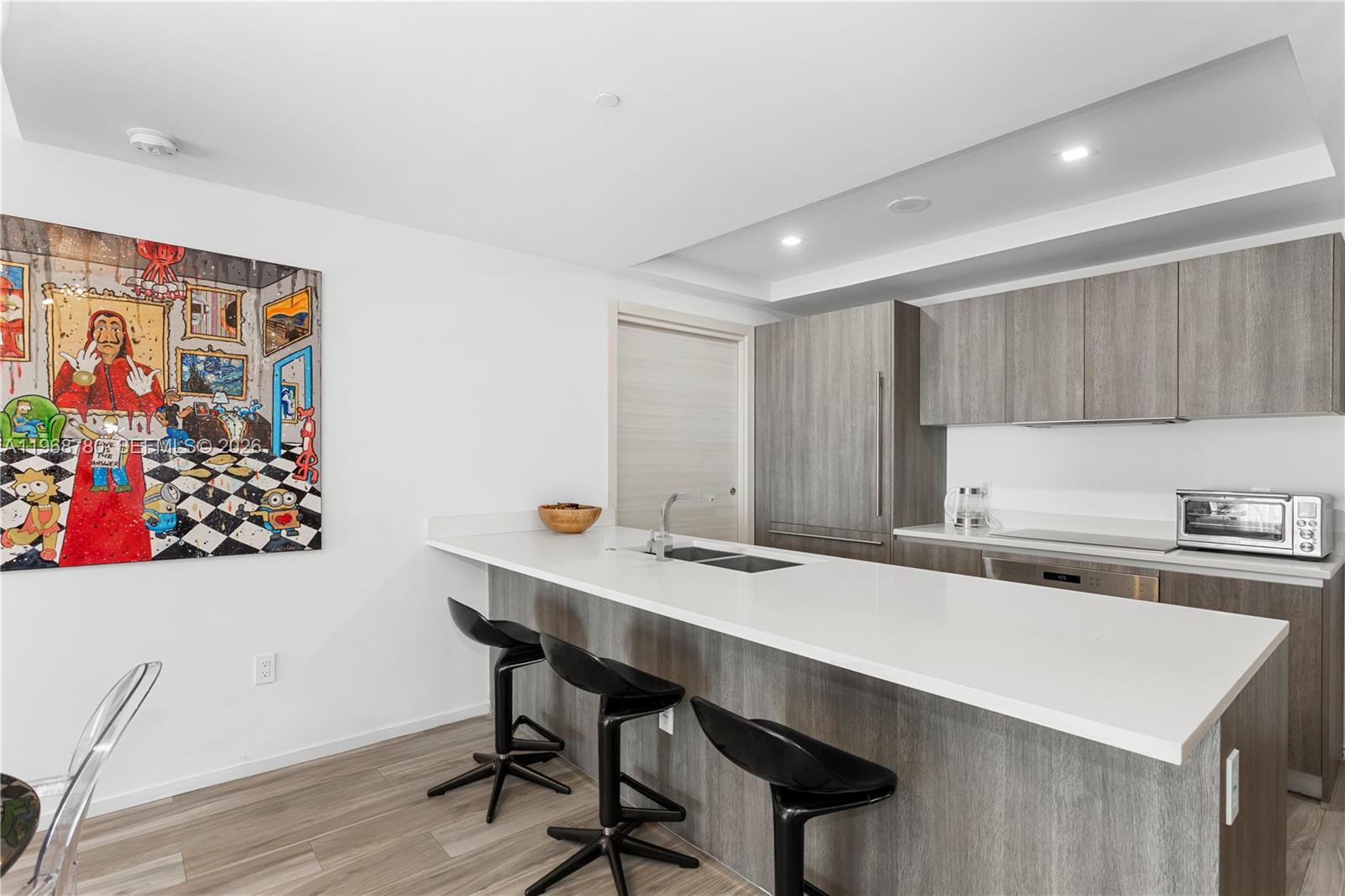 A modern kitchen features a white island with black bar stools and grey cabinetry — 801 S Miami Ave # 3310, Miami FL 33130, MIAMI, FL