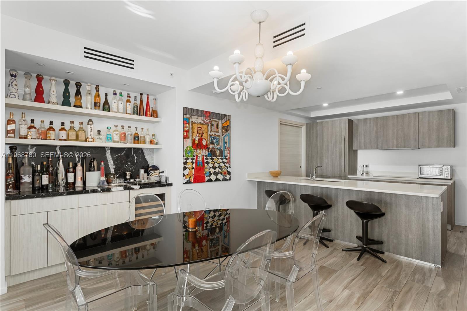 A modern dining area and kitchen featuring a bar, black table, and white chandelier — 801 S Miami Ave # 3310, Miami FL 33130, MIAMI, FL