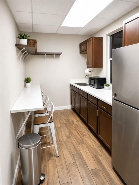 A kitchen features dark wood cabinets, a white countertop, a breakfast bar, and stainless appliances — 2506 ACORN STREET UNIT A-B, FORT PIERCE, FL