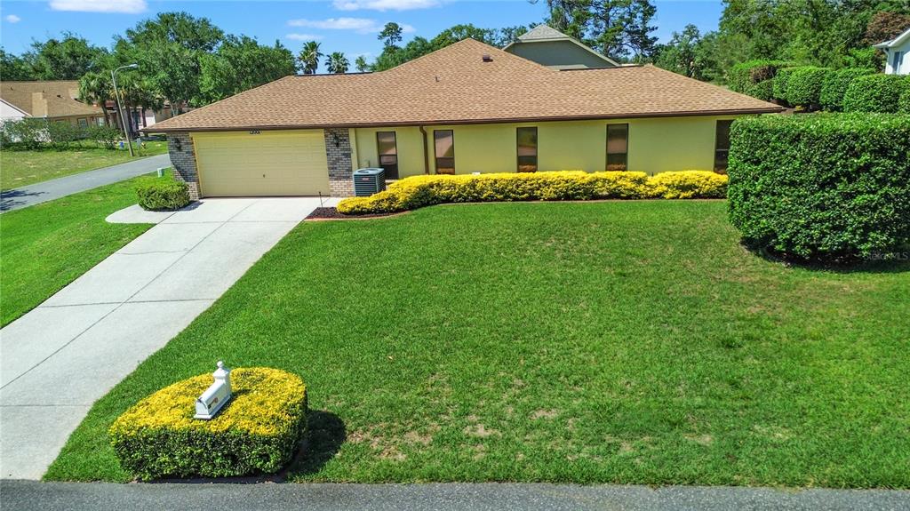 A single-story house with a tan exterior, brown roof, and a large front lawn — 12001 GRANADA PLACE, WEEKI WACHEE, FL