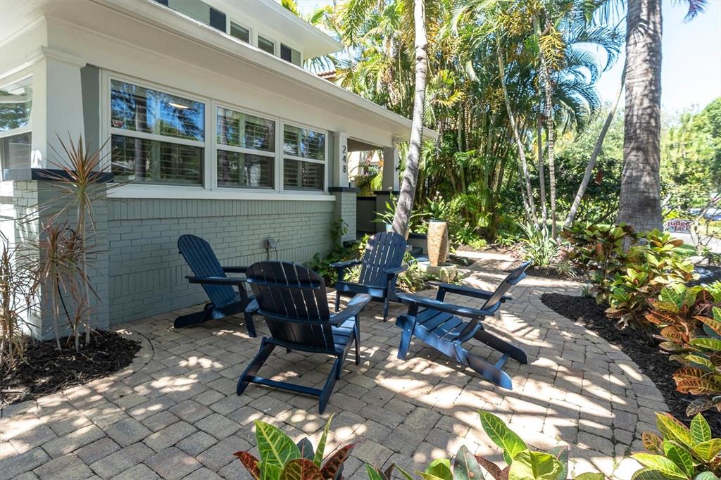 A paved patio with four dark blue Adirondack chairs sits beside a gray brick house — 248 14TH AVENUE NE, ST PETERSBURG, FL