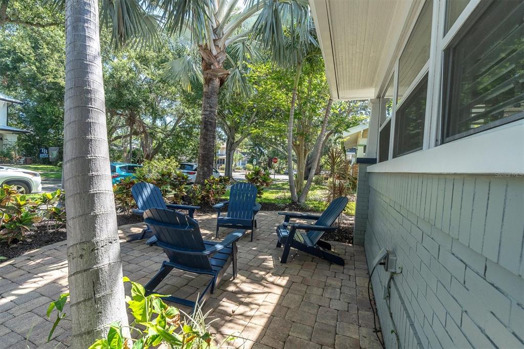 A patio with four blue Adirondack chairs sits beside a light-colored brick house exterior — 248 14TH AVENUE NE, ST PETERSBURG, FL