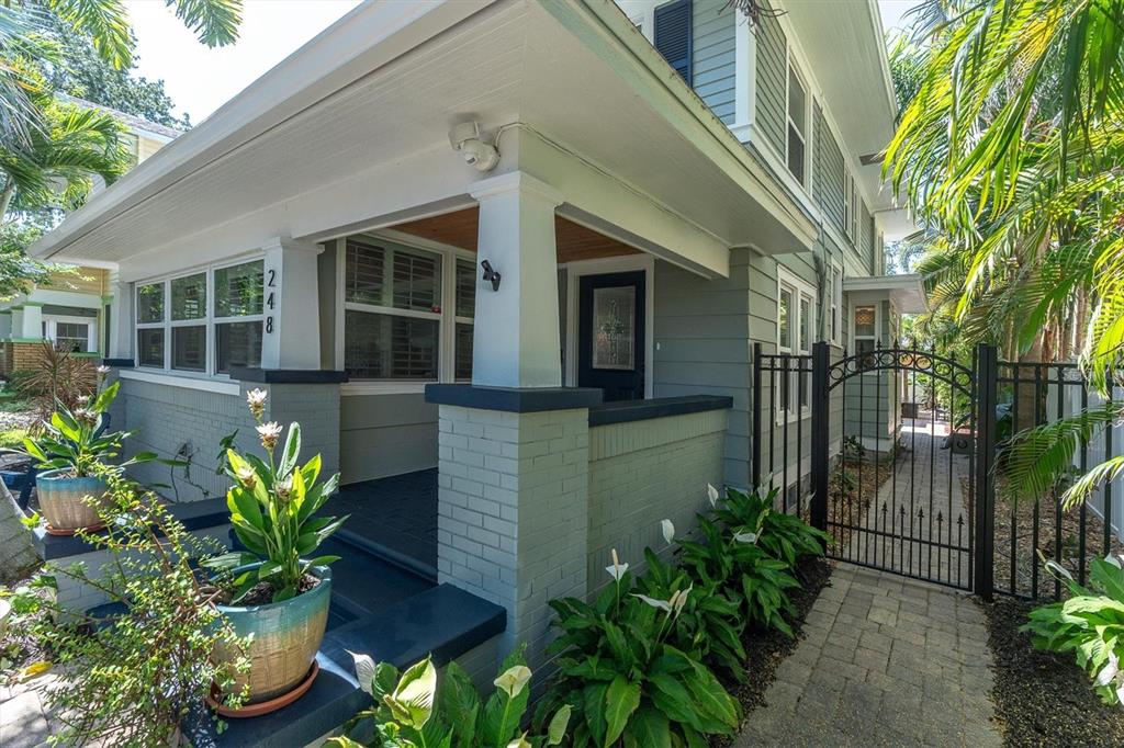 A gray house with a covered front porch, brick pillars, and a gated side walkway — 248 14TH AVENUE NE, ST PETERSBURG, FL