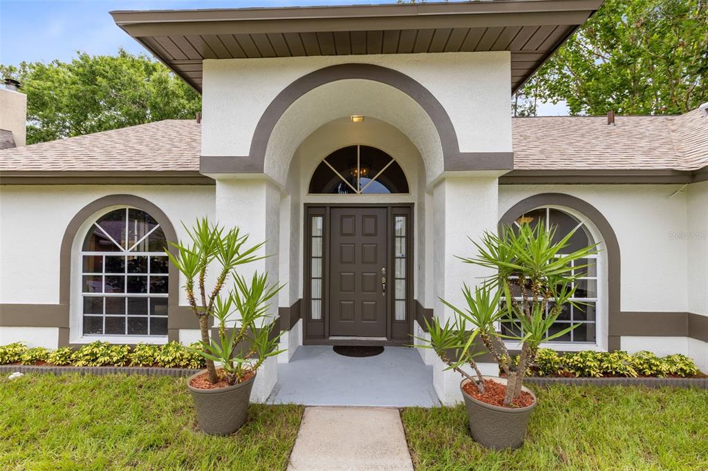 A front exterior view of a house with a central arched entryway and two windows — 5340 N LAKE BURKETT LANE, WINTER PARK, FL