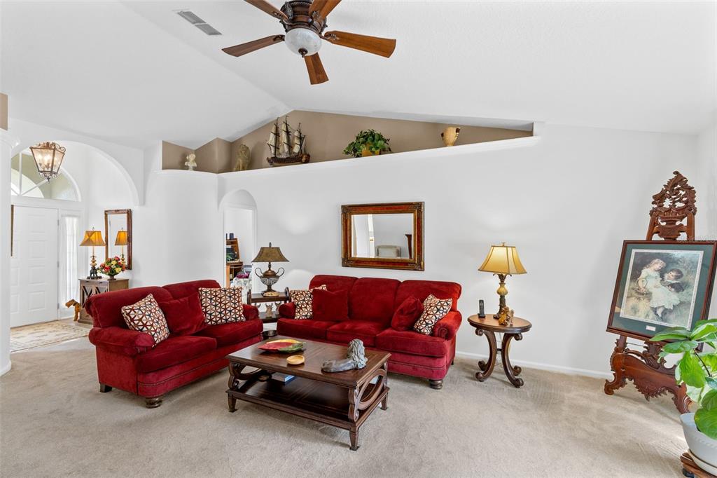 A living room with red sofas, a coffee table, vaulted ceilings, and a sliding glass door — 5340 N LAKE BURKETT LANE, WINTER PARK, FL