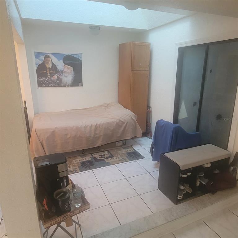 A bedroom features a bed, a tall wooden cabinet, and a shoe bench on tile flooring — 639 GOLDEN SUNSHINE CIRCLE, ORLANDO, FL