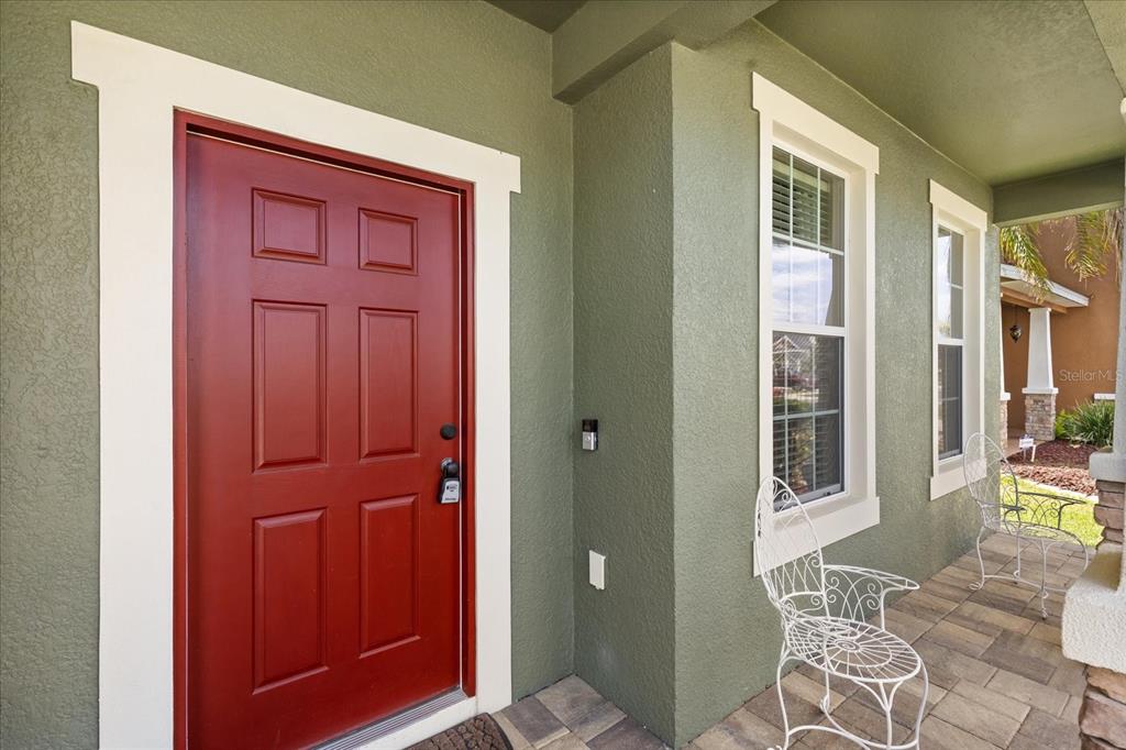 A red front door with a lockbox sits on a porch with two white chairs — 2721 WALDEN WOODS DRIVE, PLANT CITY, FL