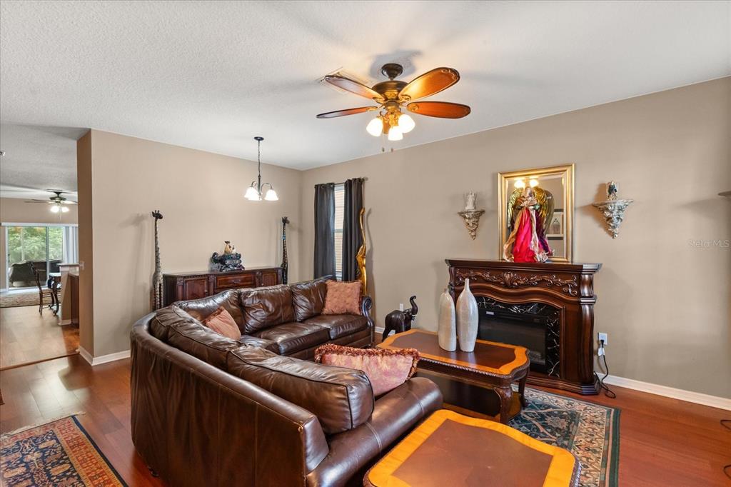 A living room features a brown leather sectional, a fireplace, and a ceiling fan — 2721 WALDEN WOODS DRIVE, PLANT CITY, FL