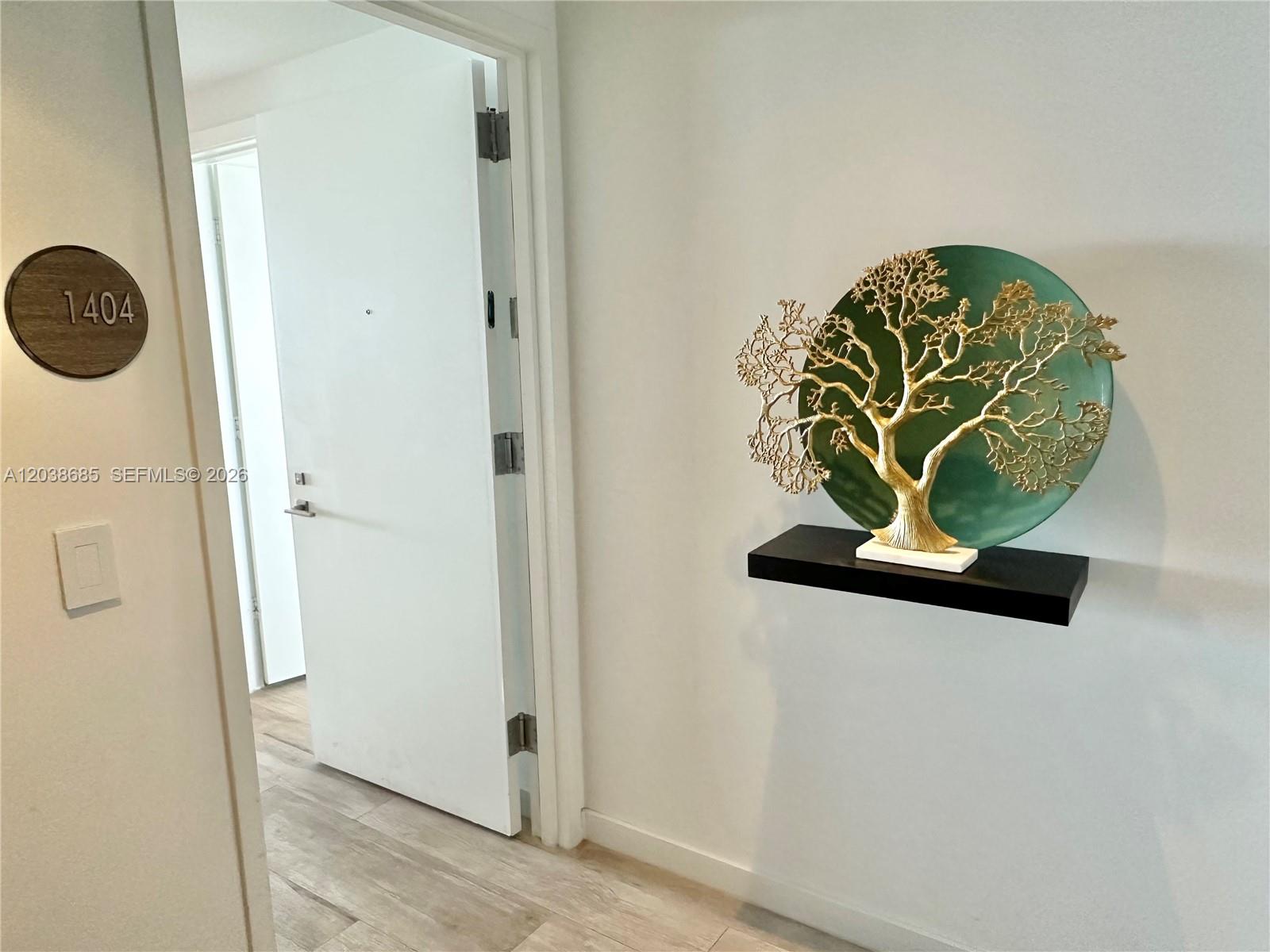 A white hallway features a door labeled 1404 and a gold tree sculpture on a shelf — 650 NE 32nd St # 1404, Miami FL 33137, MIAMI, FL