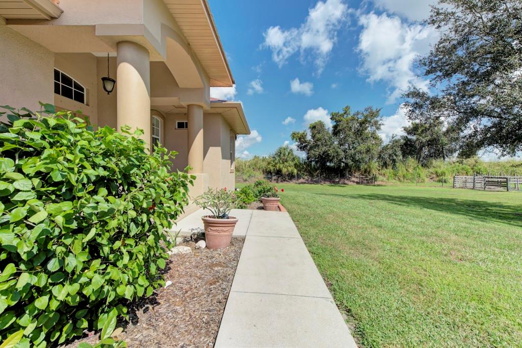 A concrete walkway leads along the side of a house past potted plants and landscaping — 6930 69TH STREET E, PALMETTO, FL