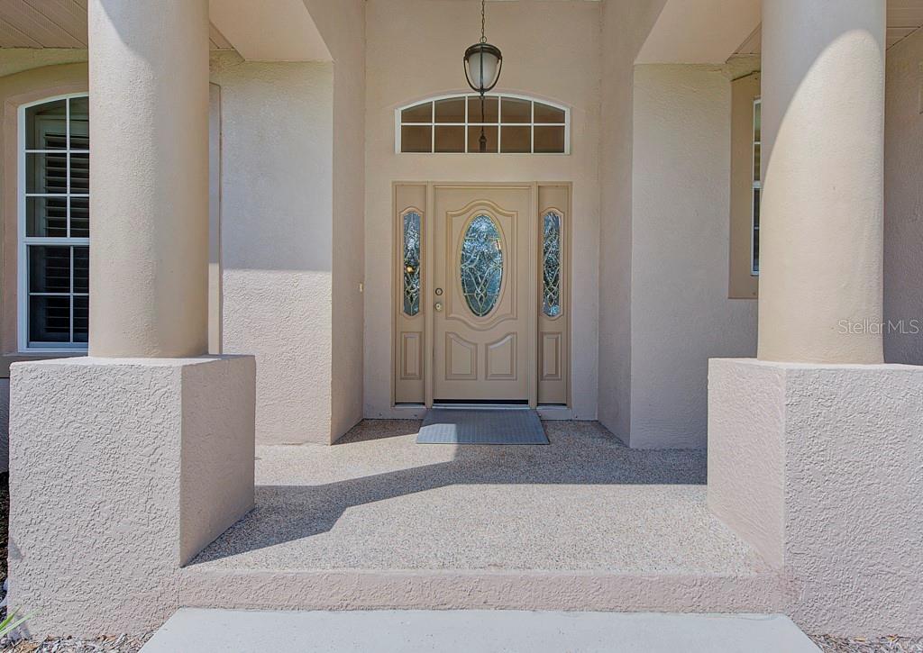 The exterior front entrance features a beige door with sidelights, columns, and a concrete porch — 6930 69TH STREET E, PALMETTO, FL
