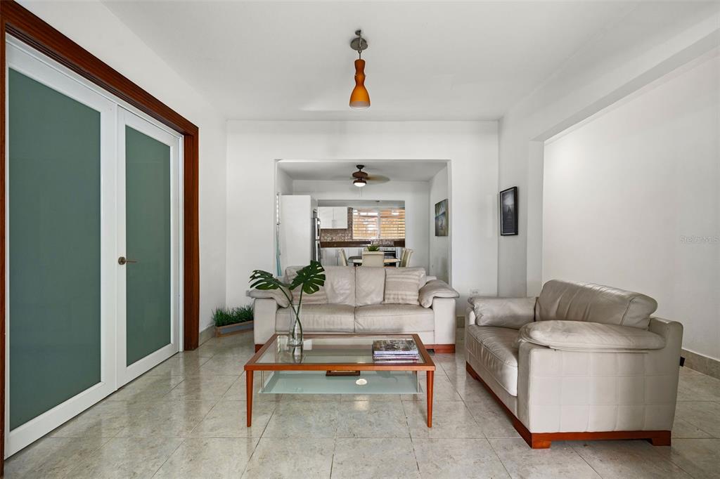 A living room with light tile floors, two beige sofas, and a glass coffee table — Ocean Park 2052 CACIQUE, SAN JUAN, PR