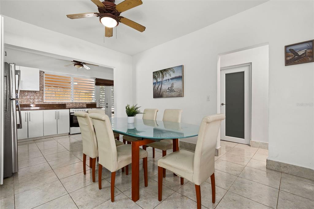A dining area with a glass table and chairs sits adjacent to a white kitchen — Ocean Park 2052 CACIQUE, SAN JUAN, PR