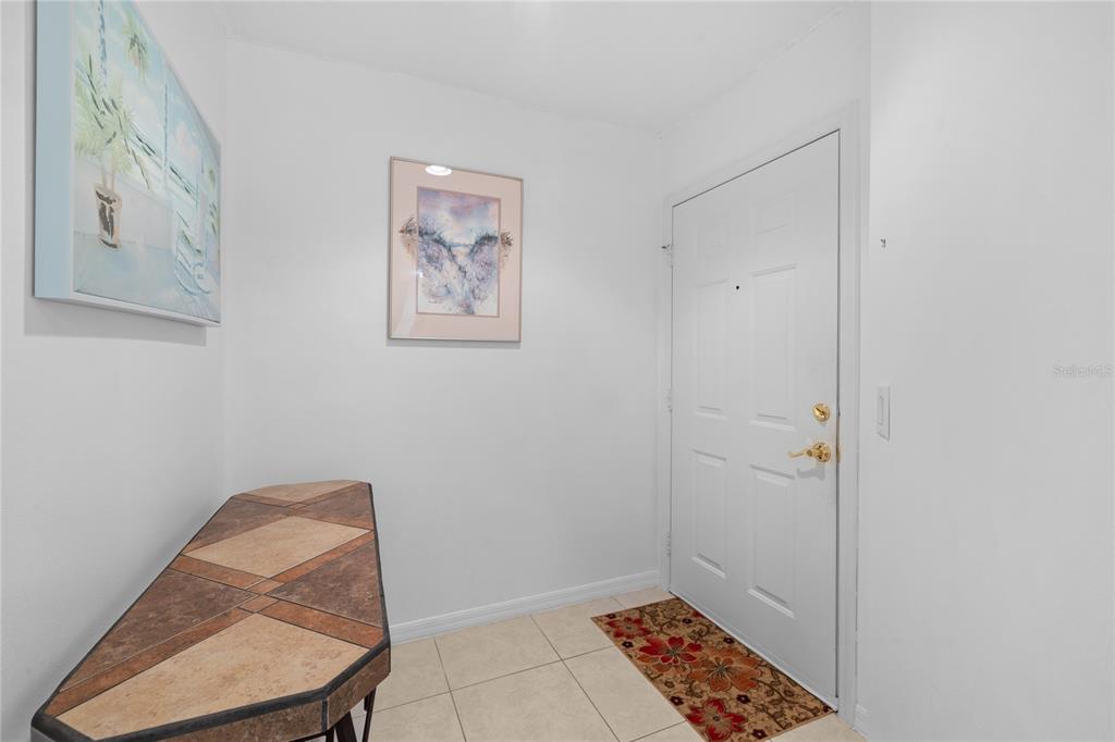 An entryway features a tiled floor, a white door, and a console table — 4244 CENTRAL SARASOTA PARKWAY UNIT 716, SARASOTA, FL