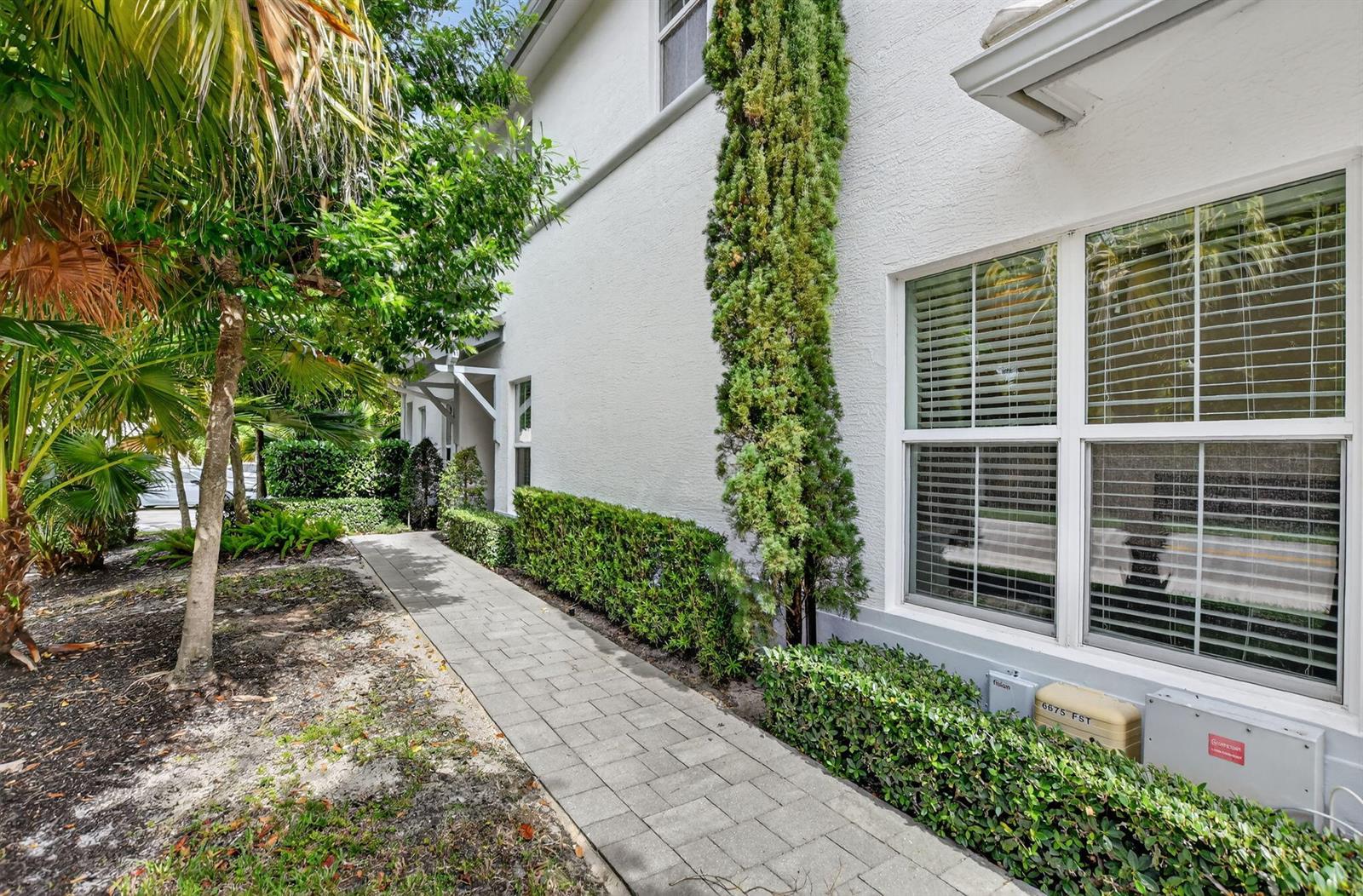 A paved walkway leads along the side of a white house with a landscaped hedge — 6675 Quiet Wave Trail # 91, Boca Raton FL 33433, BOCA RATON, FL