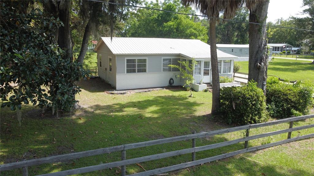 A light-colored house with a metal roof sits on a grassy lot with trees — 2995 NE 97TH STREET ROAD, ANTHONY, FL