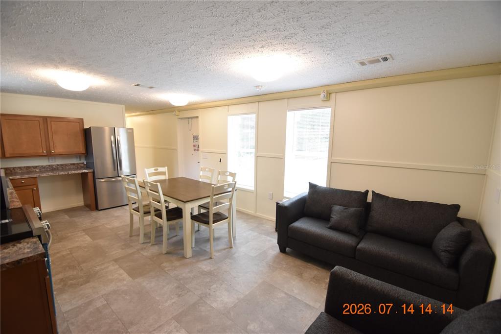 An open-concept living and dining area features tile flooring, a dark sofa, and a kitchen — 6560 W AVOCADO STREET, CRYSTAL RIVER, FL