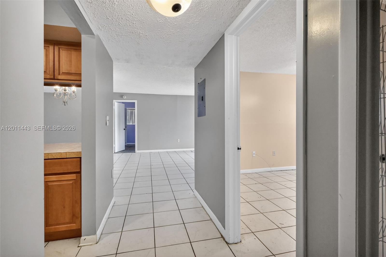 A hallway with white tile floors leads to an open living area and a bedroom — 20731 NE 4th Pl # 104, Miami FL 33179, MIAMI, FL