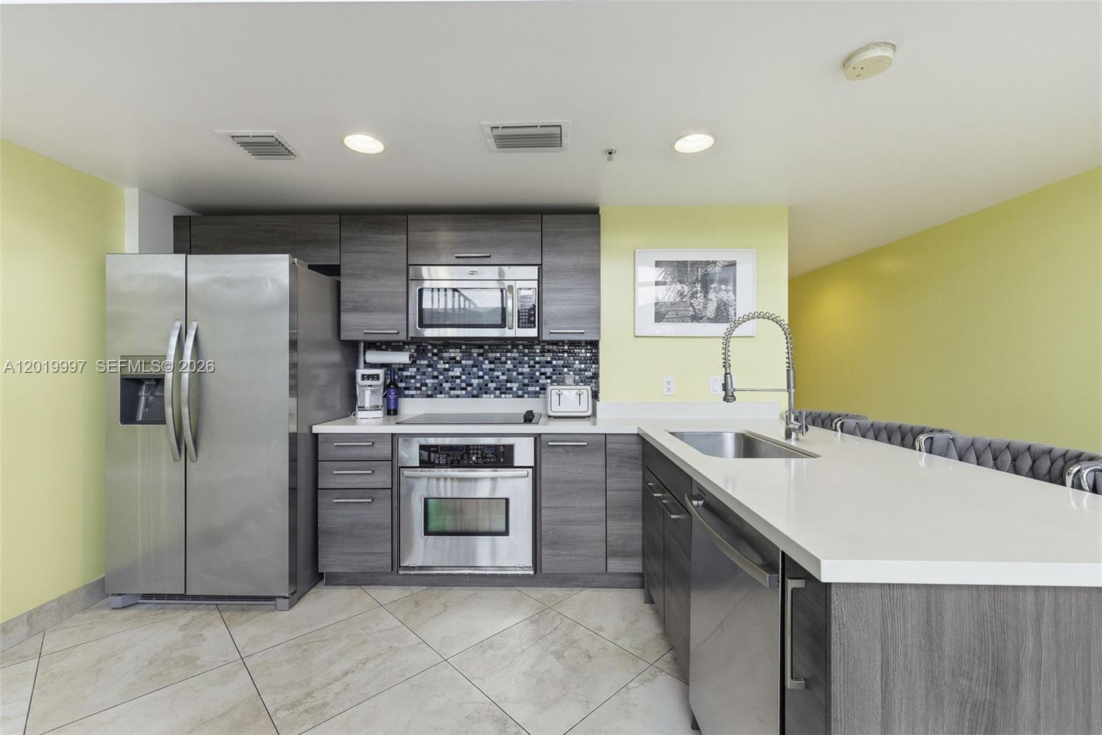A kitchen features gray cabinetry, stainless steel appliances, a white countertop, and light yellow walls — 421 Meridian Ave # 16, Miami Beach FL 33139, MIAMI BEACH, FL