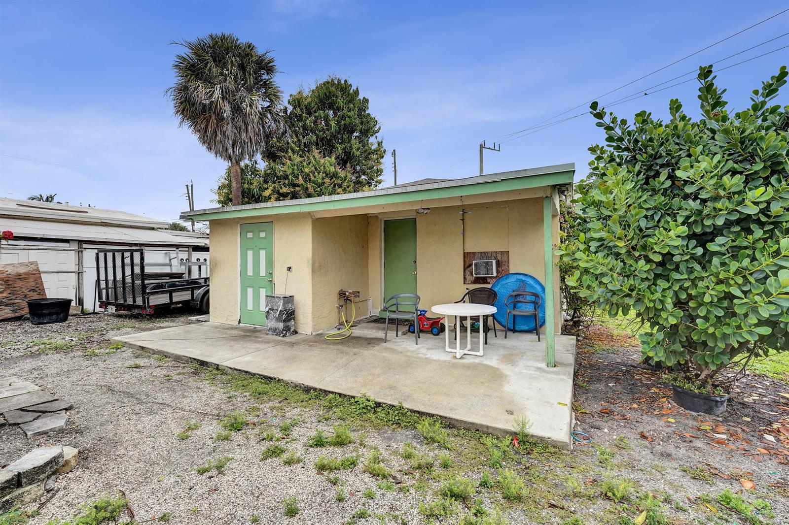 A small, yellow, single-story building with a concrete patio and two green doors — 1412 B Nw 7 Street, Pompano Beach FL 33069, POMPANO BEACH, FL
