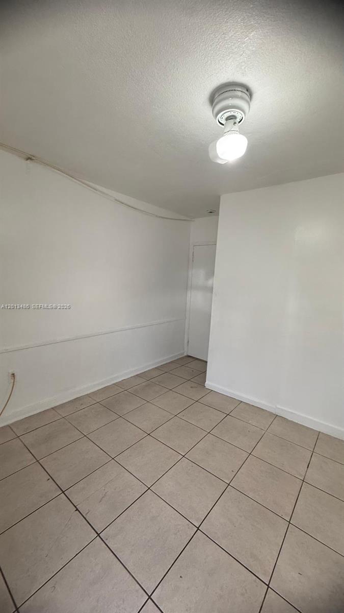 A small, empty room features white walls, a tiled floor, and a ceiling light fixture — 725 Opa Locka Blvd # C, Opa-Locka FL 33054, OPA-LOCKA, FL
