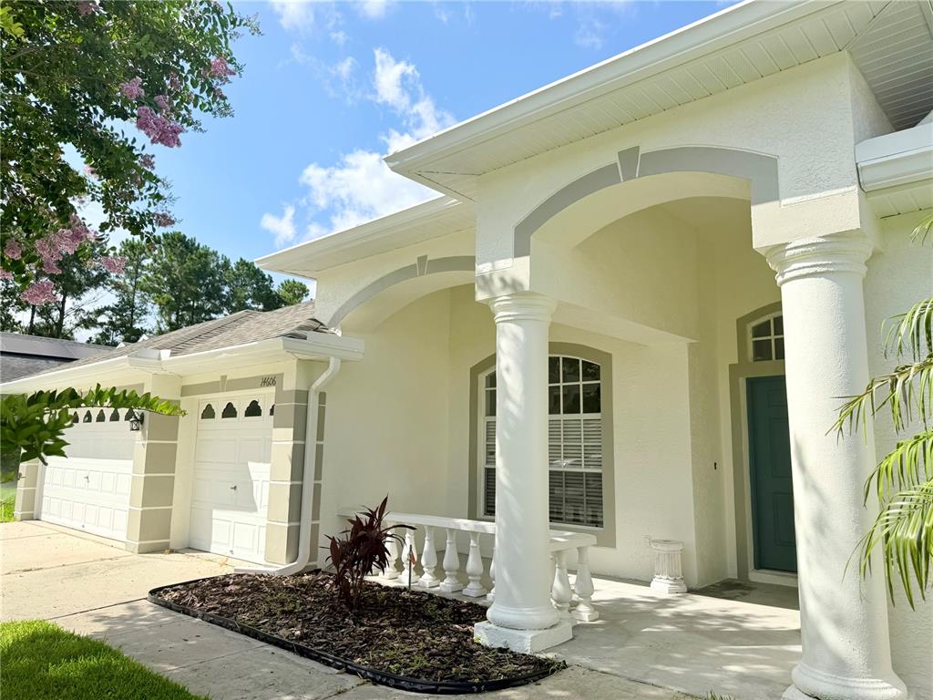 A light-colored house exterior features a covered porch with white columns and a garage — 14606 CORAL BERRY DRIVE, TAMPA, FL