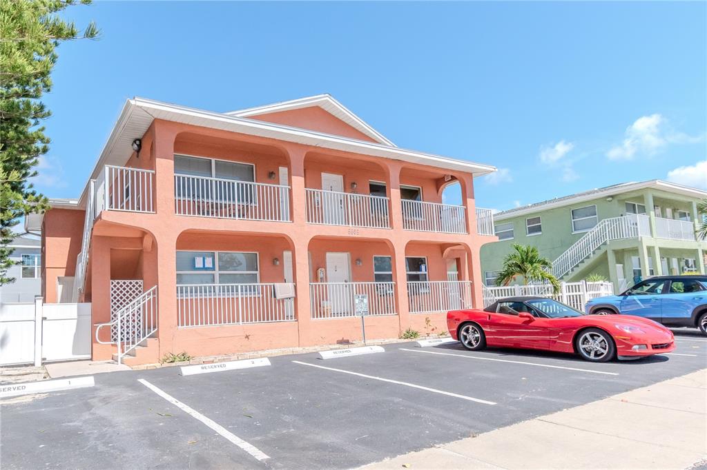 A two-story peach-colored apartment building features white railings and a parking lot out front — 5605 SHORE BOULEVARD S UNIT 1B, GULFPORT, FL