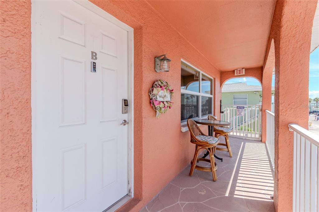 An exterior view of a balcony featuring a white door, seating, and a wreath — 5605 SHORE BOULEVARD S UNIT 1B, GULFPORT, FL
