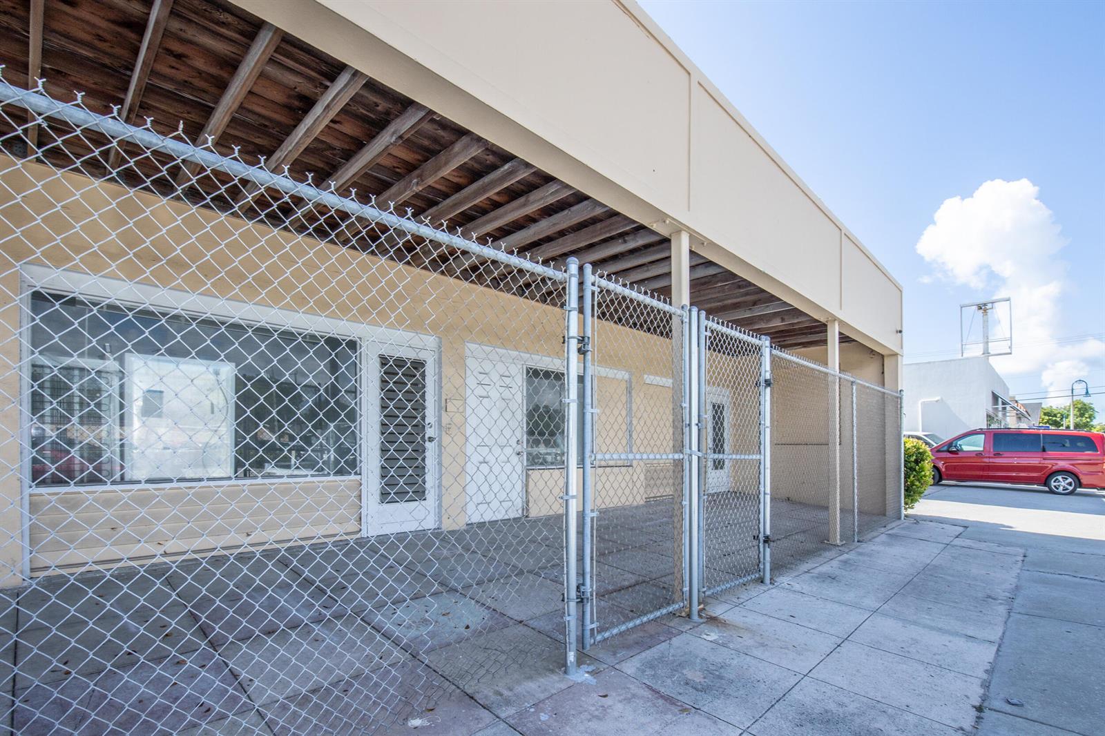 A beige commercial building exterior features a chain-link fence enclosing a concrete front patio area — 922 S Dixie Highway, FL 33460, FL
