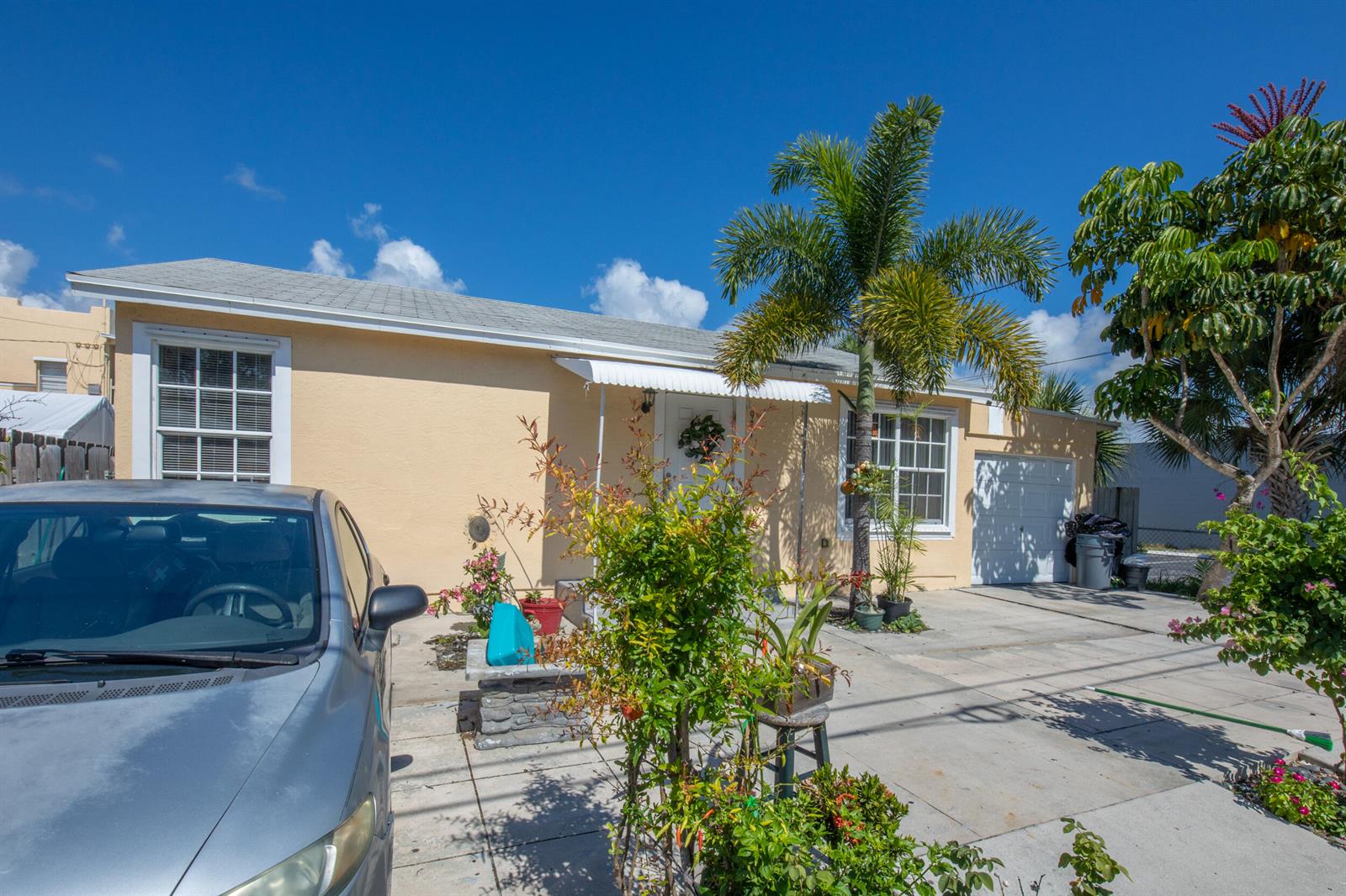 A single-story beige house with a palm tree, a front driveway, and a parked car — 922 S Dixie Highway, FL 33460, FL