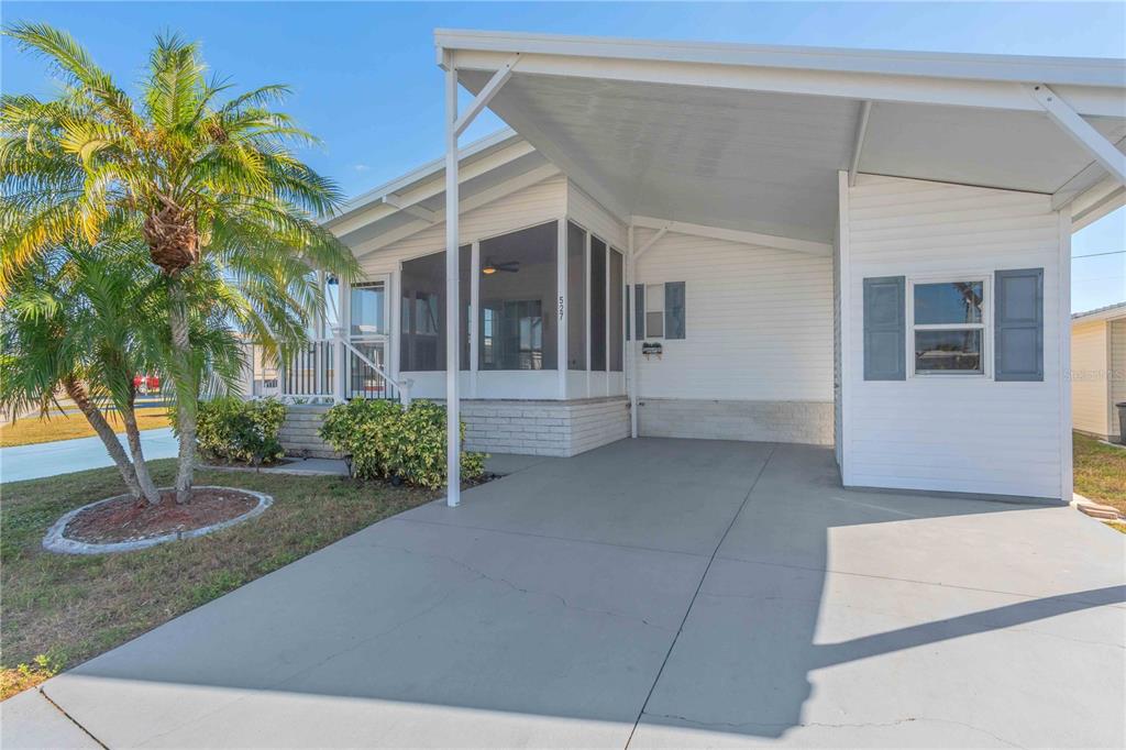 A white manufactured home with a screened-in porch, a carport, and a palm tree — 527 FLEETWOOD STREET, NORTH PORT, FL