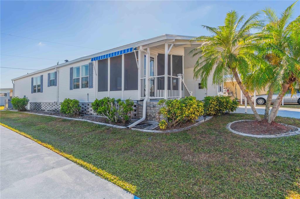 A single-story manufactured home with a screened-in porch and a palm tree in the yard — 527 FLEETWOOD STREET, NORTH PORT, FL