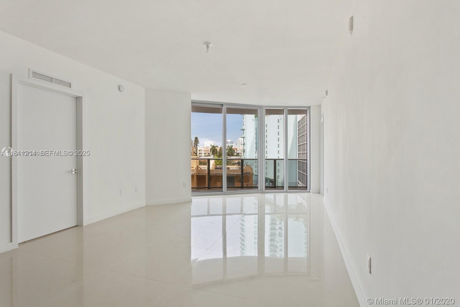 An empty room with white walls, glossy tile flooring, and floor-to-ceiling windows leading to a balcony — 488 NE 18th St # 501, Miami FL 33132, MIAMI, FL