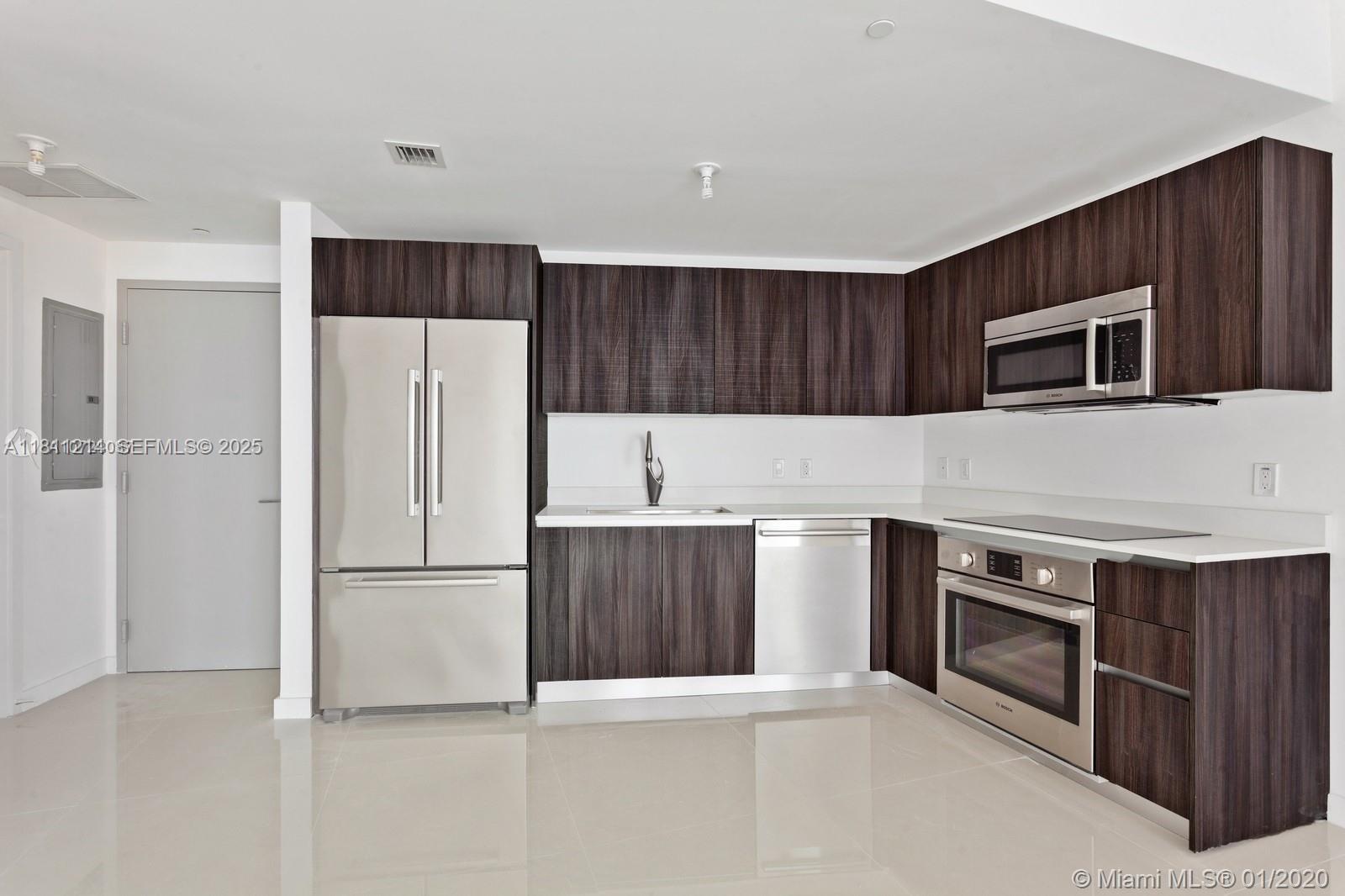 A modern kitchen features dark wood cabinetry, stainless steel appliances, and white countertops — 488 NE 18th St # 501, Miami FL 33132, MIAMI, FL