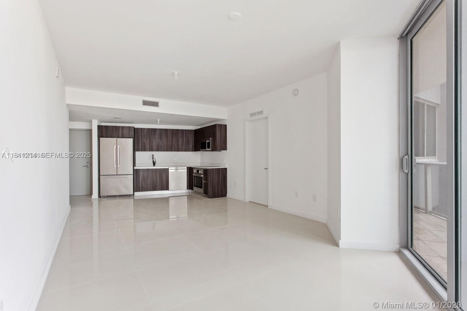 An open-concept kitchen with dark wood cabinetry and stainless steel appliances overlooks a tiled living area — 488 NE 18th St # 501, Miami FL 33132, MIAMI, FL