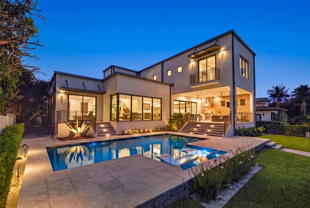 A modern two-story house with a swimming pool, patio, and outdoor kitchen at dusk — 874 PLACIDO WAY NE, ST PETERSBURG, FL
