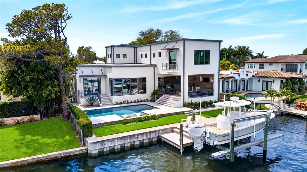 A modern white waterfront house features a swimming pool, a boat lift, and a dock — 874 PLACIDO WAY NE, ST PETERSBURG, FL
