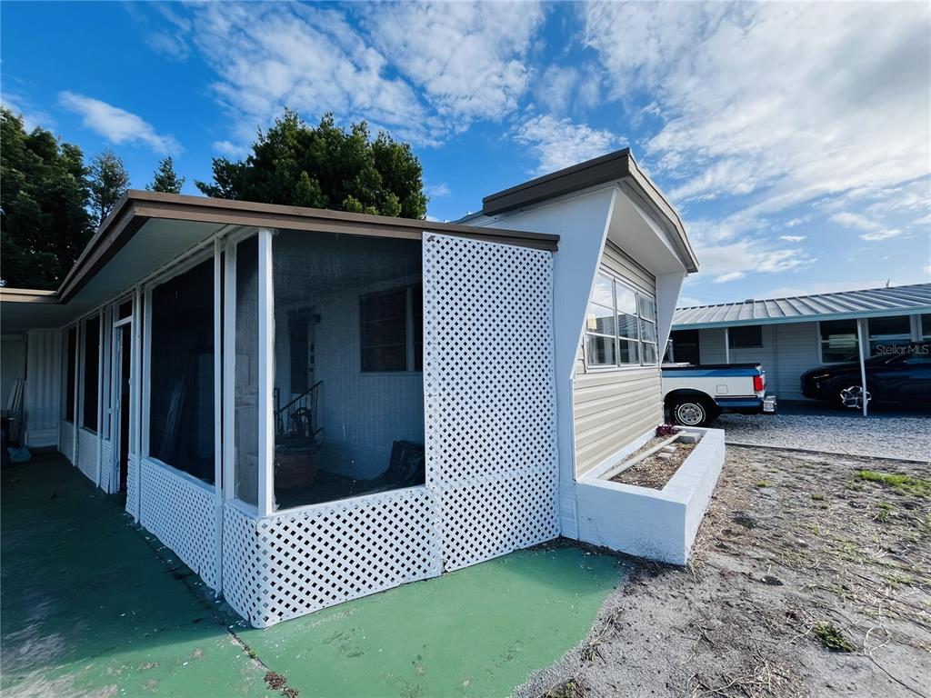 A mobile home exterior features a screened-in porch with white lattice skirting and a planter — 2113 ILLINOIS AVENUE, BRADENTON, FL
